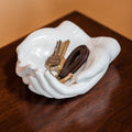White cupped-hands trinket tray holding keys for styling
