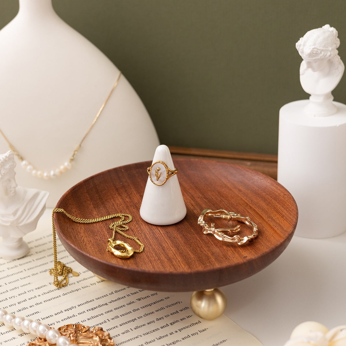 Round wooden trinket tray with gold-coloured feet; jewellery and decorative objects shown for styling